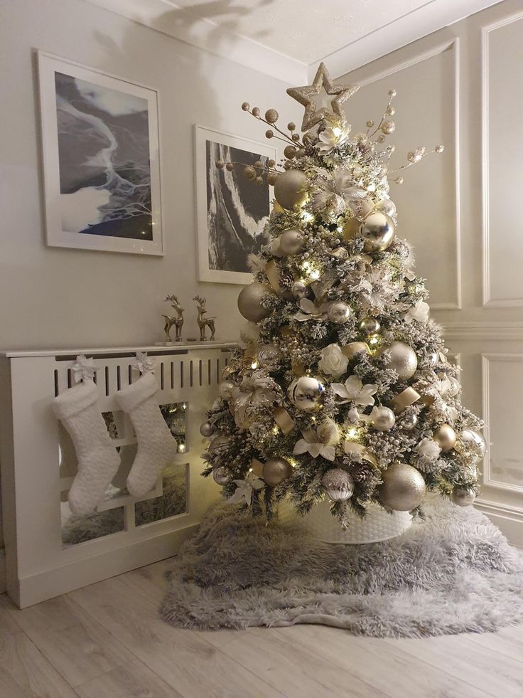 a white christmas tree with silver and gold ornaments in a room decorated for the holidays