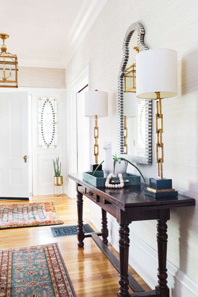 a hallway with a table, lamp and rug