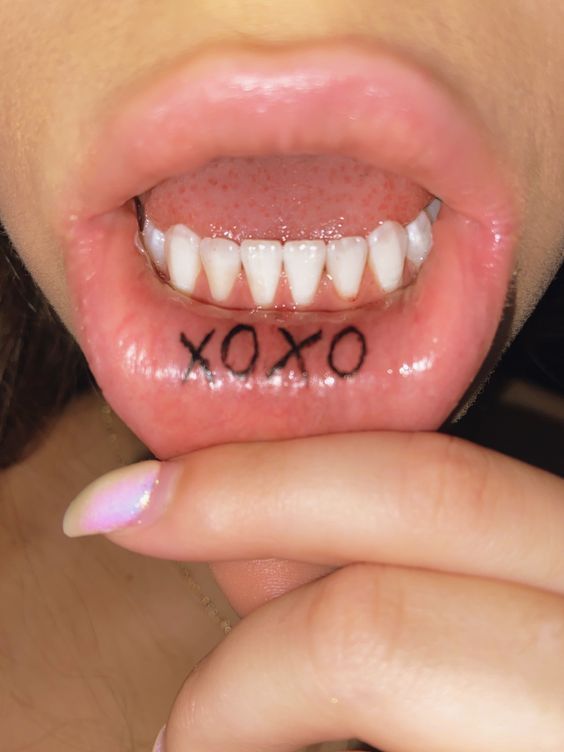 a close up of a person's tongue with the word xoxo written on it