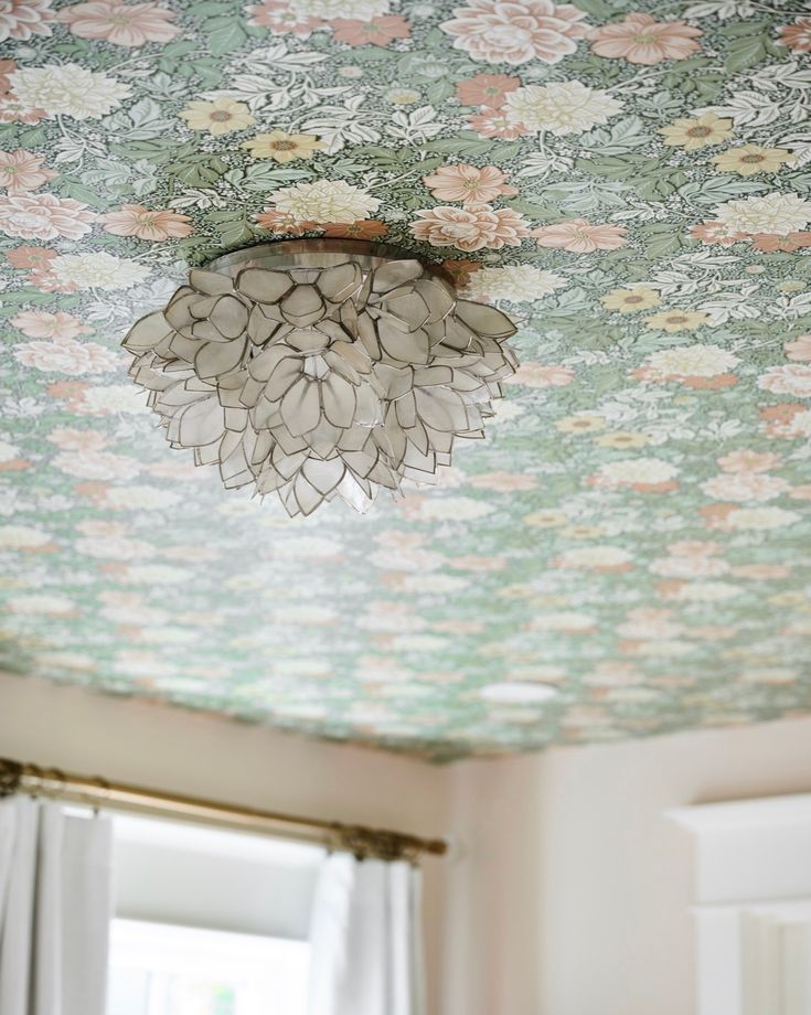 a chandelier hanging from the ceiling in a room with floral wallpaper on it