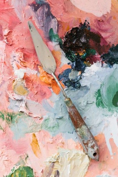 an artist's palette and paintbrush sitting on top of a piece of art