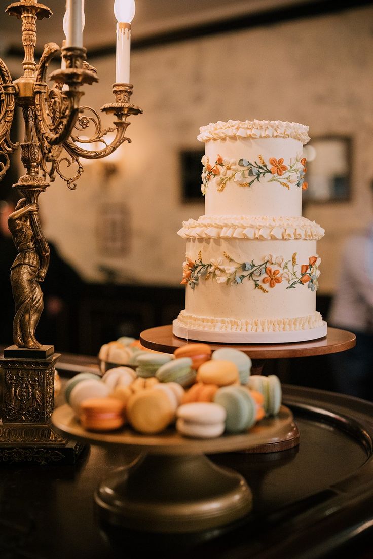 a three tiered cake sitting on top of a table next to a candelabra