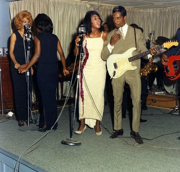 a man and woman singing into microphones while standing next to each other with guitars in front of them