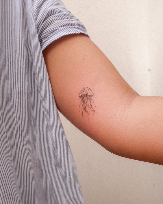 a person with a tattoo on their arm that has a small jellyfish in it