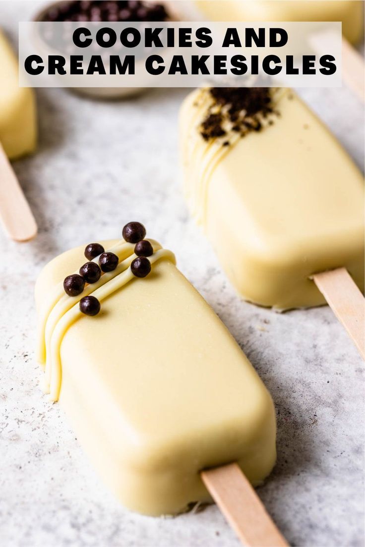 three popsicles with toppings on them sitting on a counter next to spoons