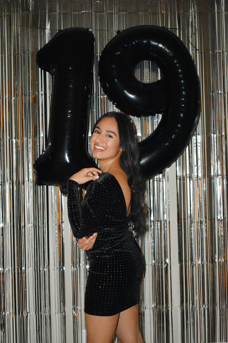 a woman standing in front of a giant number balloon