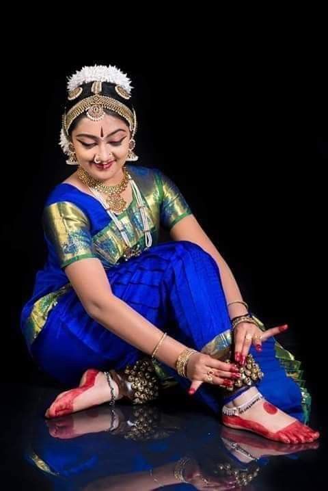 a woman sitting on the ground in a blue sari with her hands clasped together