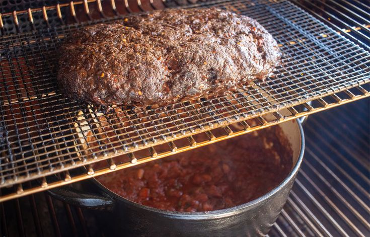 meatloaf being cooked on the grill in an oven with a pot full of sauce