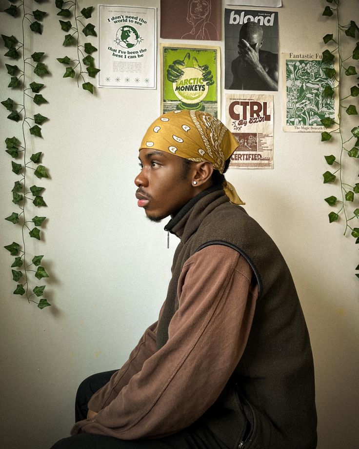 a man sitting in front of a wall covered with posters