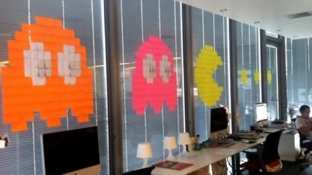 people are sitting at desks in an office decorated with sticky notes on the walls