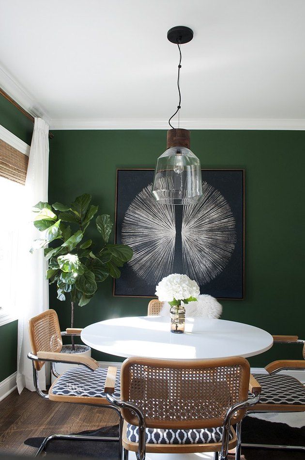 a dining room with green walls and white table surrounded by chairs in front of a painting