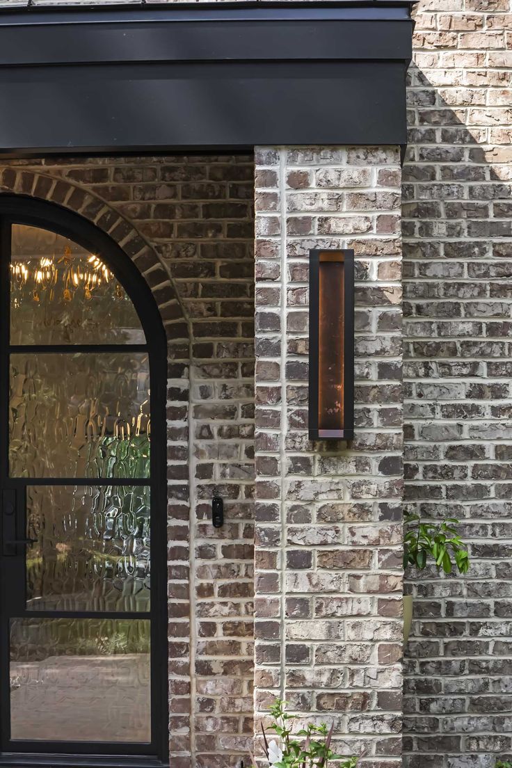 a clock on the side of a brick building next to a planter with flowers