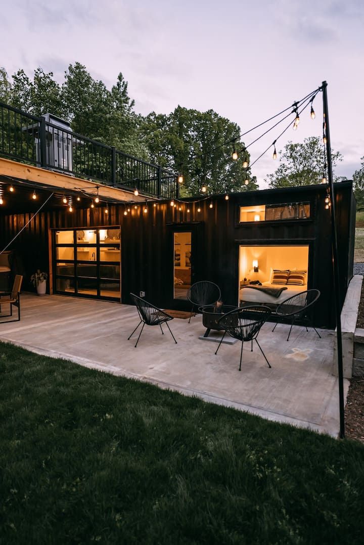 an outdoor living area with patio furniture and string lights on the roof, surrounded by grass