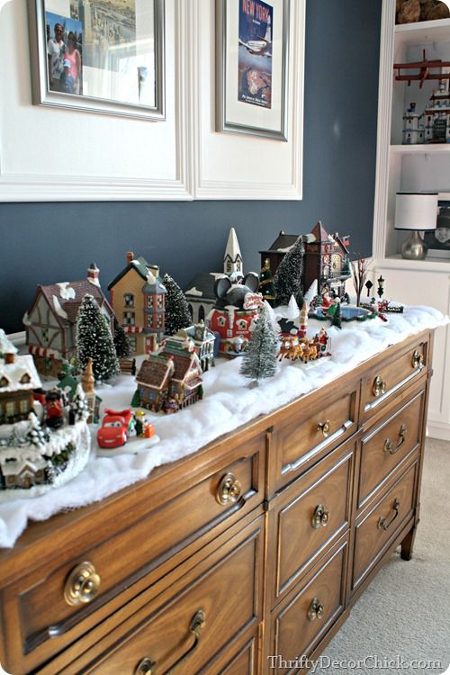 a christmas display on top of a dresser in a room with blue walls and white trim