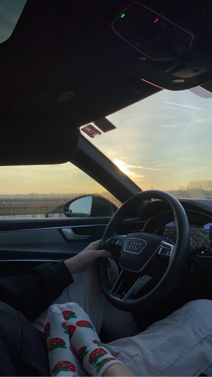 a person sitting in the driver's seat of a car with their hands on the steering wheel