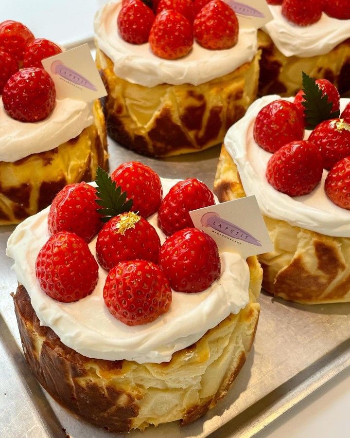 several cakes with white frosting and strawberries on top are sitting on a tray