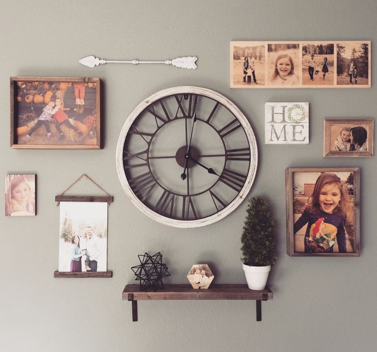 a large clock mounted to the side of a wall next to pictures and a potted plant