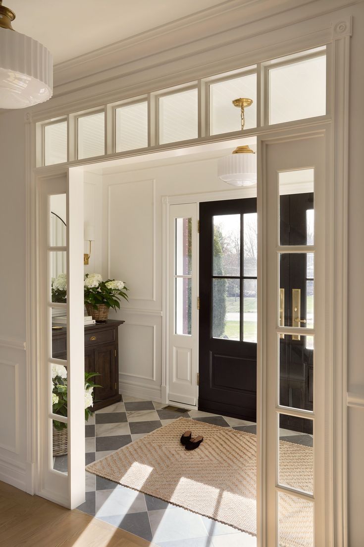 an open door leading into a room with a checkered floor and large windows on the wall