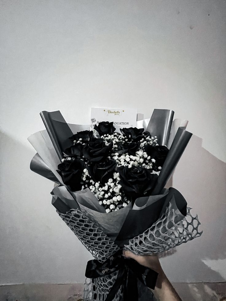 a person holding a bouquet of flowers in front of a white wall with writing on it