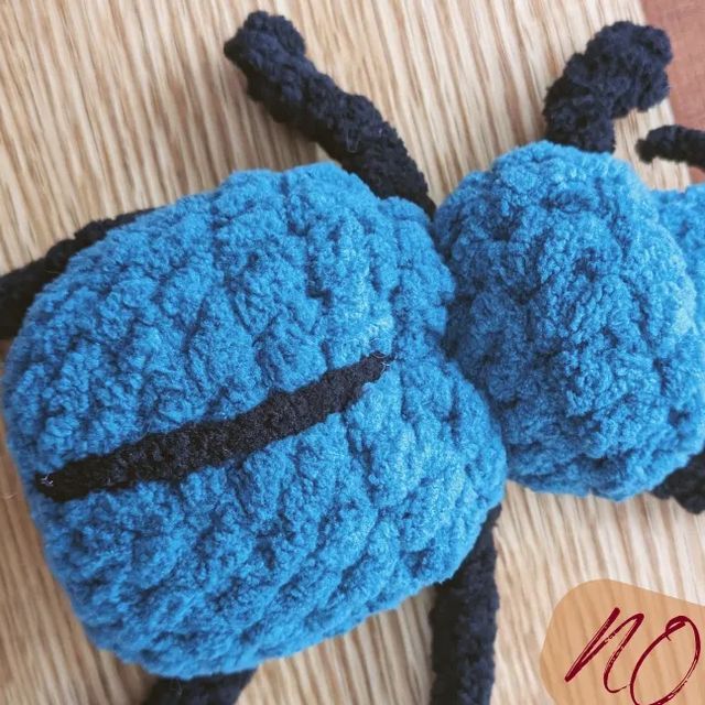 there is a crocheted blue stuffed bug on the floor