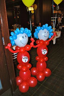 two balloons shaped like people with blue hair are standing in the middle of a room