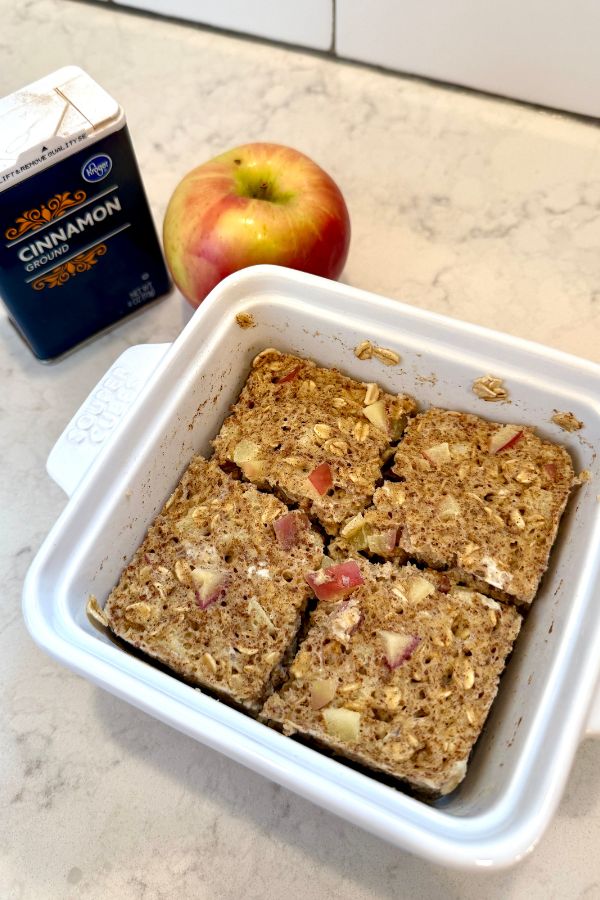 an apple and oatmeal snack in a baking dish next to a carton of cinnamon apples