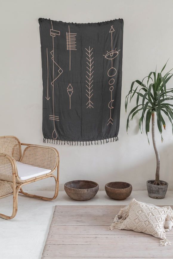 a wall hanging in a living room next to two chairs and a potted plant