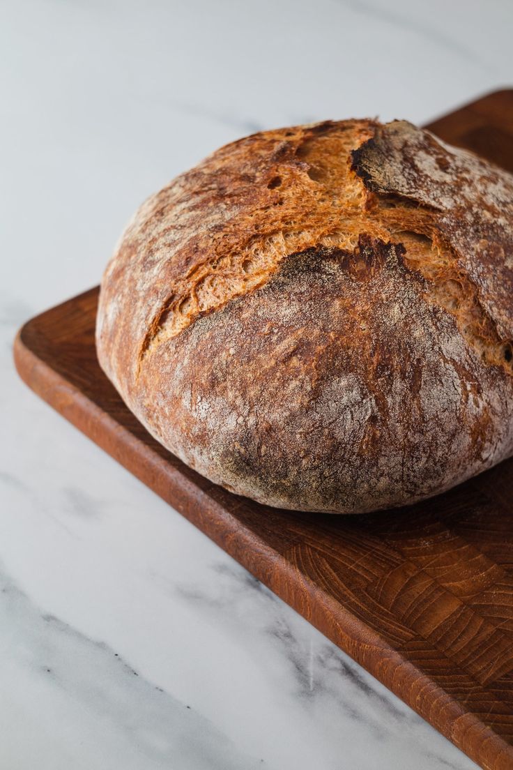 a loaf of bread sitting on top of a wooden cutting board