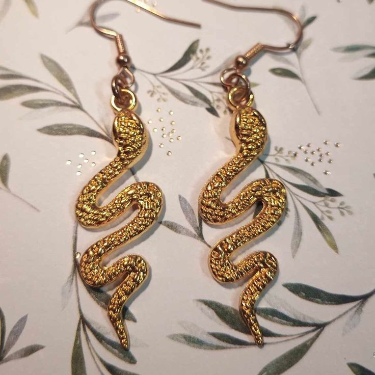 These lovely gold snake earrings are a statement piece. Gold Snake Shape Jewelry For Parties, Gold Snake-shaped Party Jewelry, Gold Snake-shaped Jewelry For Party, Handmade Elegant Snake Earrings, Gold Snake-shaped Earrings With Pierced Ears, Handmade Gold Snake-shaped Earrings, Gold Snake-shaped Jewelry With Pierced Ears, Gold Snake Jewelry For Pierced Ears, Elegant Handmade Snake Earrings