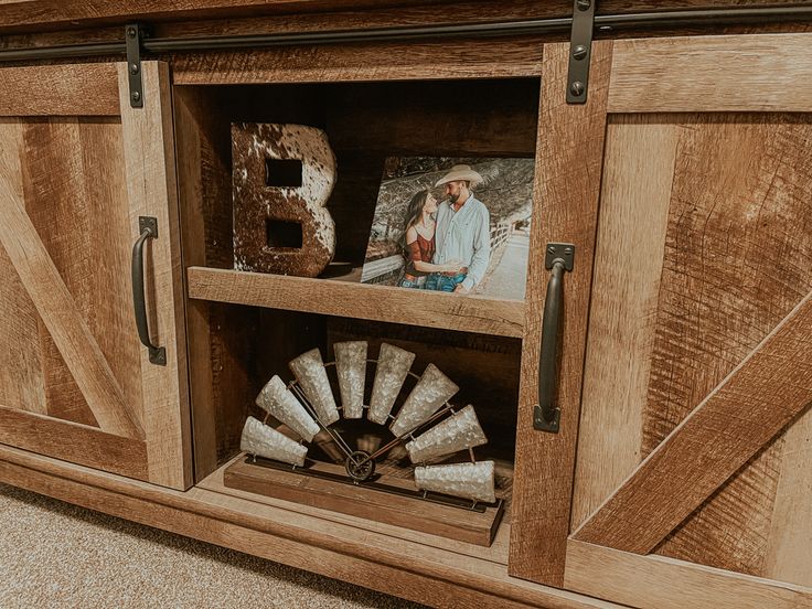 a close up of a wooden cabinet with pictures on the front and side doors open