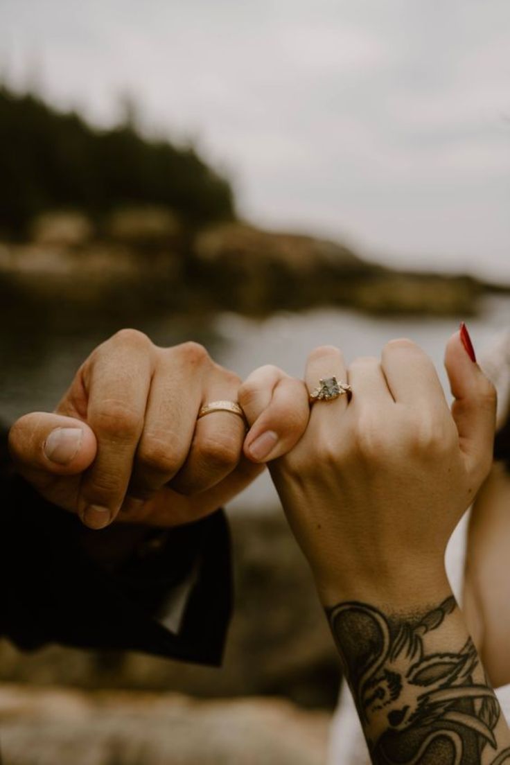 a man and woman holding hands while standing next to each other with tattoos on their arms