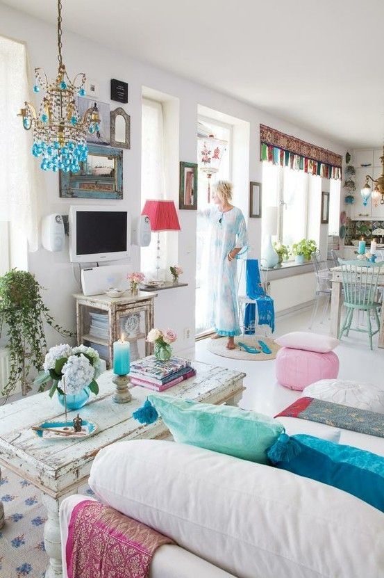 a living room filled with white furniture and lots of colorful pillows on top of it