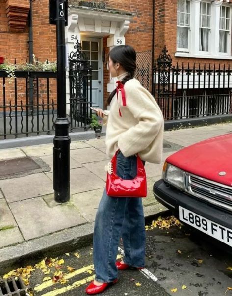 a woman standing next to a red car