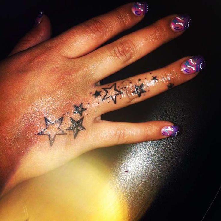 a woman's hand with stars tattooed on it