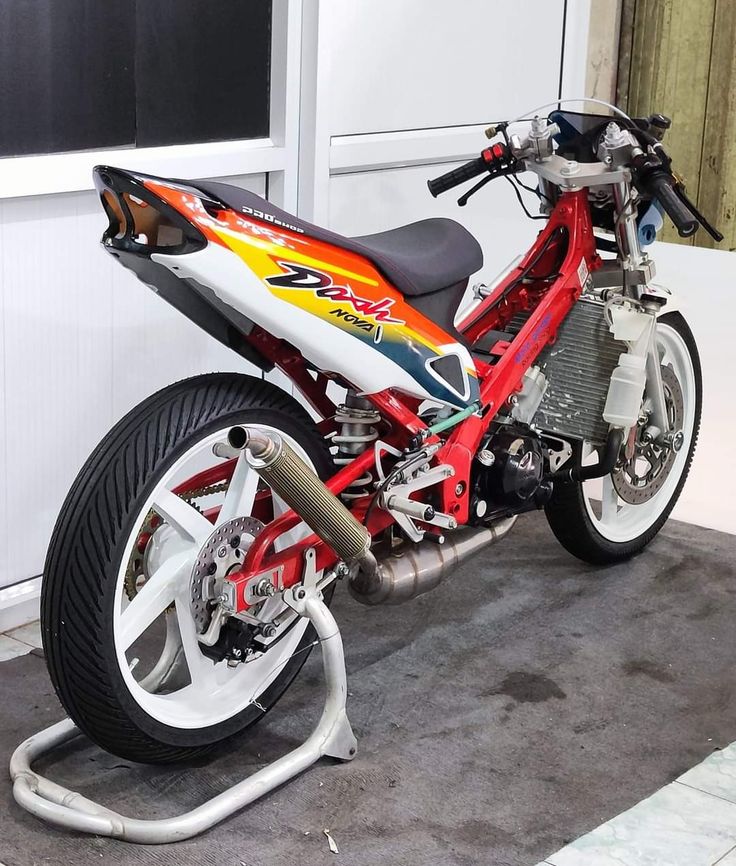 a red and white motorcycle parked in front of a garage