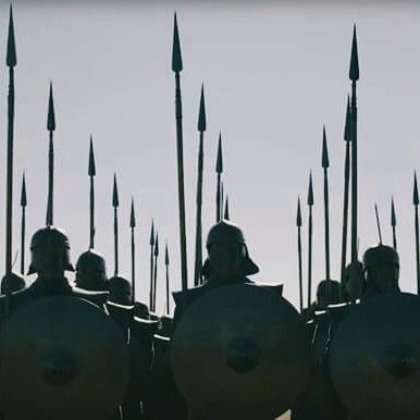 a group of men in armor standing next to each other with spears sticking out of their mouths