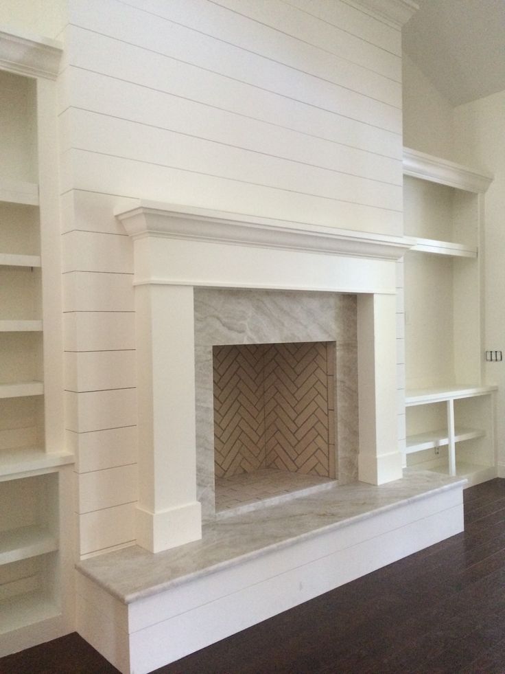 an empty living room with a fireplace and bookcases