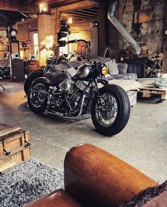 a motorcycle is parked in a garage with other motorcycles and boxes on the floor next to it