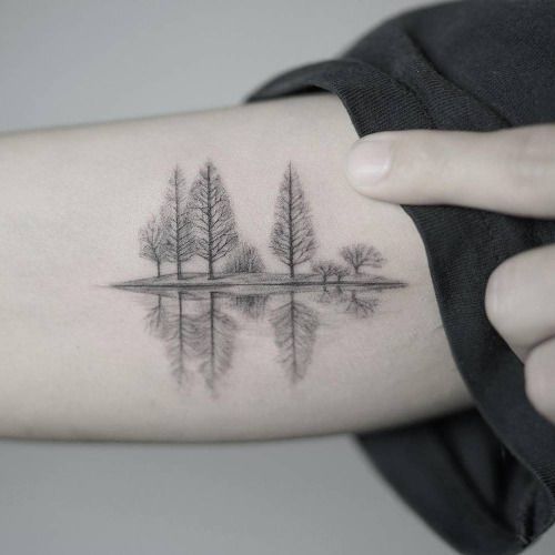 a woman's arm with trees and water on it