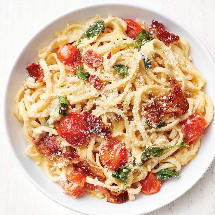 a white plate topped with pasta covered in tomato sauce and parmesan sprinkles