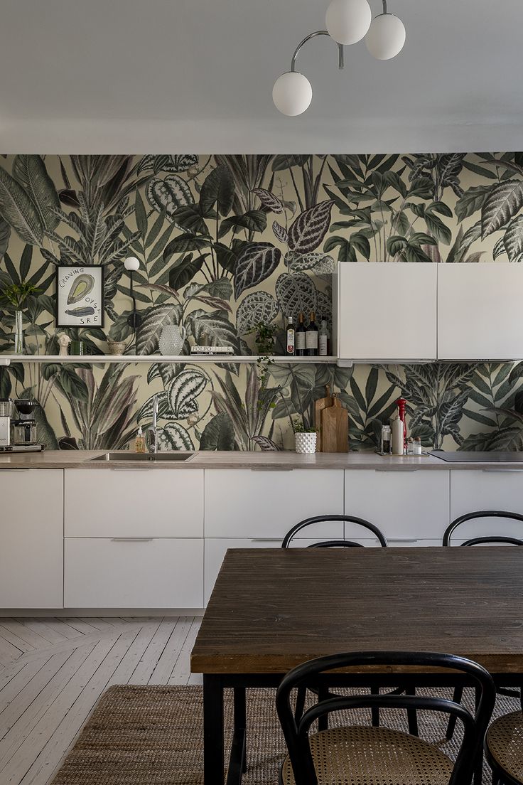 a kitchen with a table and chairs in front of a wallpapered backsplash