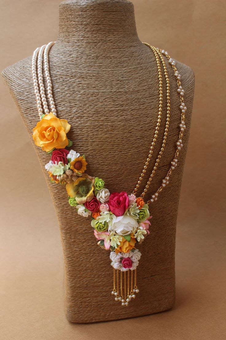 a mannequin with flowers and pearls on it's neck, including two necklaces