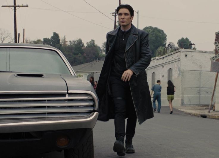 a man walking down the street in front of a car