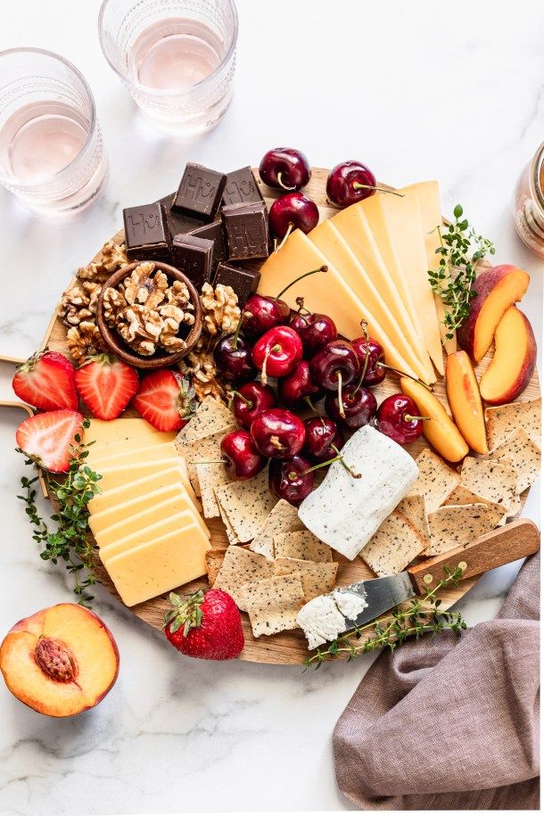 an assortment of cheeses, fruit and nuts on a platter