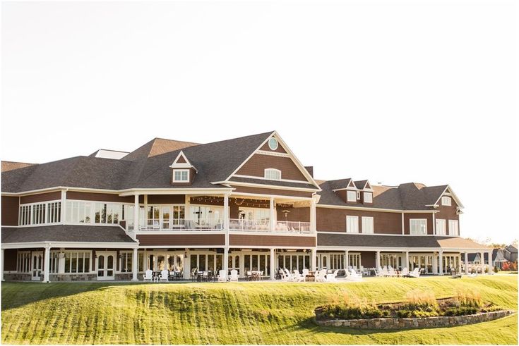 a large brown and white house sitting on top of a lush green field