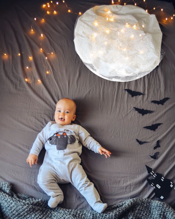 a baby laying on top of a bed next to bats