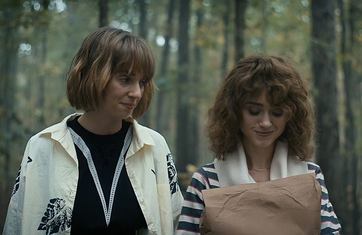 two women standing next to each other in the woods