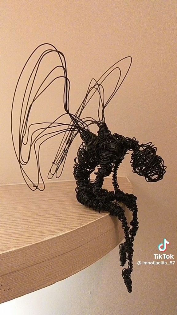 a wire sculpture sitting on top of a wooden shelf