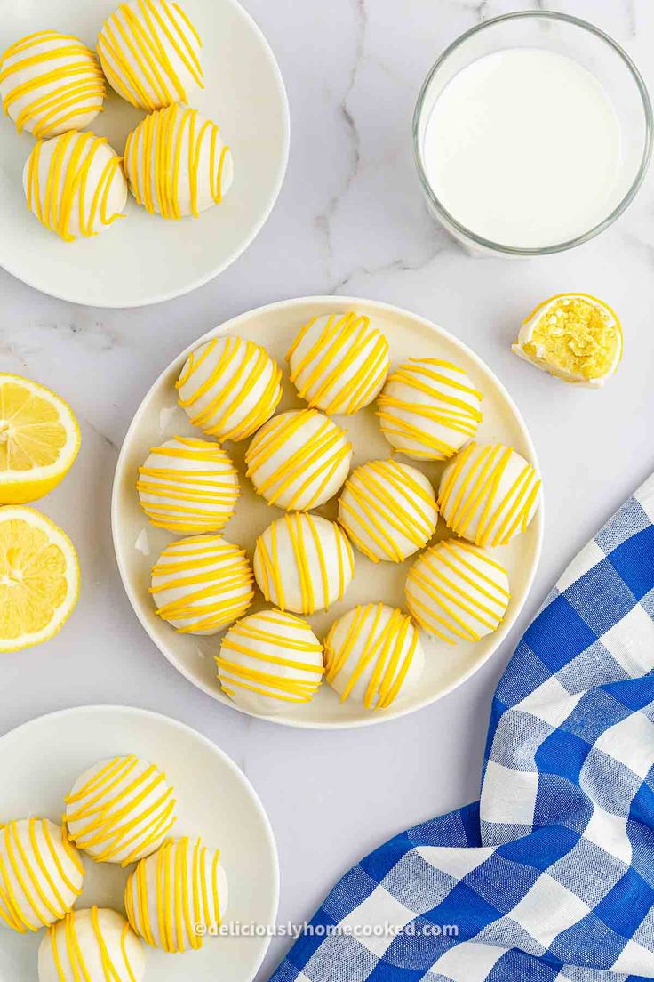 two plates with yellow striped cookies next to a glass of milk and lemons on the table