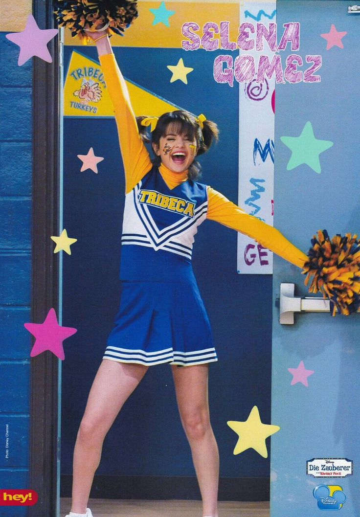 a cheerleader posing in front of a door with her hands up to the side